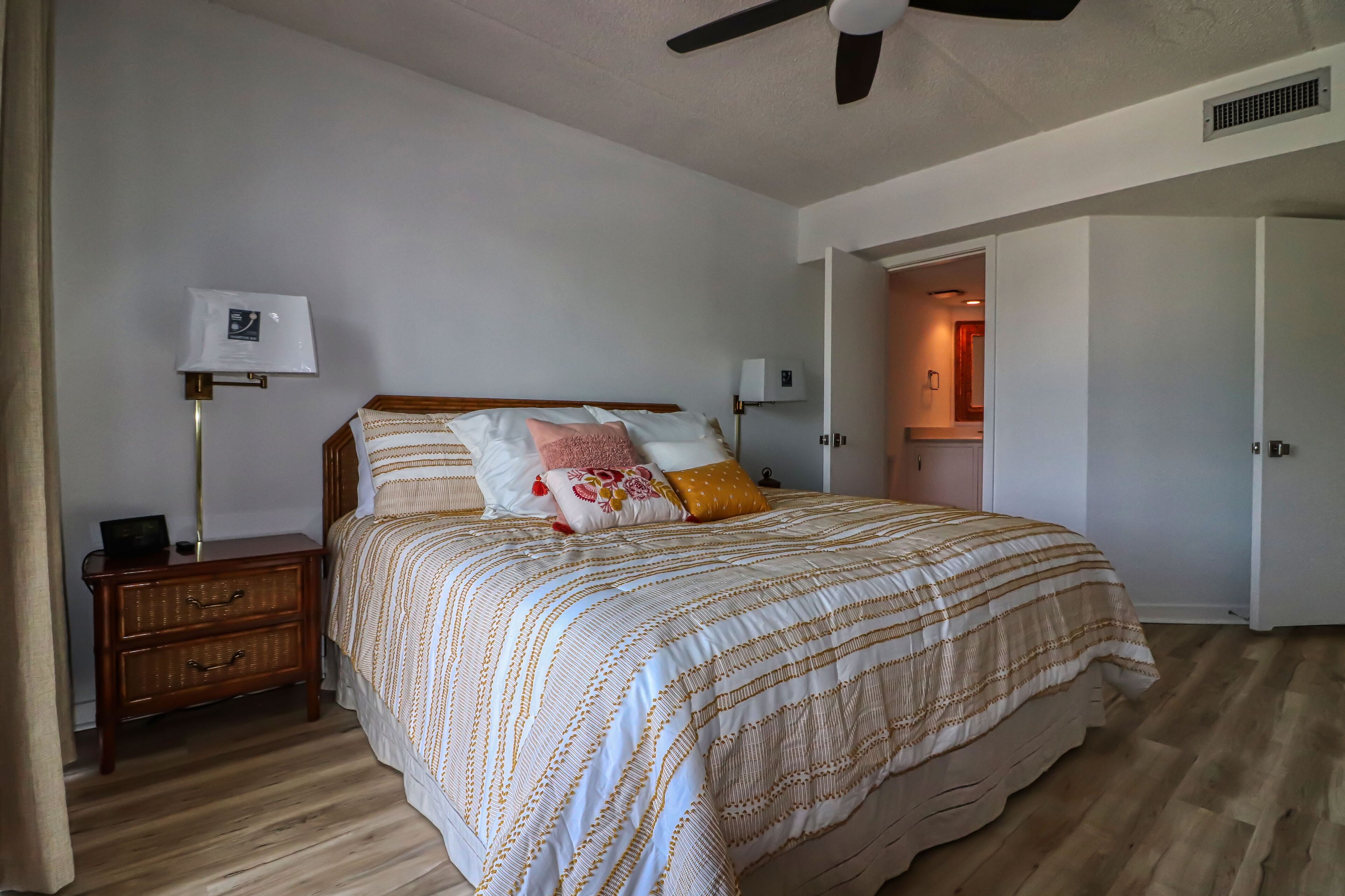 Ein Schlafzimmer mit Bett, Nachttisch, Lampe und Deckenventilator.