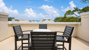 A rooftop terrace with a table and four chairs, overlooking a coastal area with buildings and trees. - Ocean View Rooftop ☀️Heated Pool, 1 Minute to Beach, 4 Story Home ☀️ Beach Gear (Santa Rosa Beach)