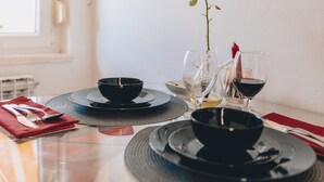 Une table à manger avec des bols noirs, des verres à vin et un vase contenant une plante.