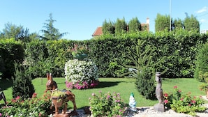 Un jardín con estatuas, un seto y un muro de piedra.