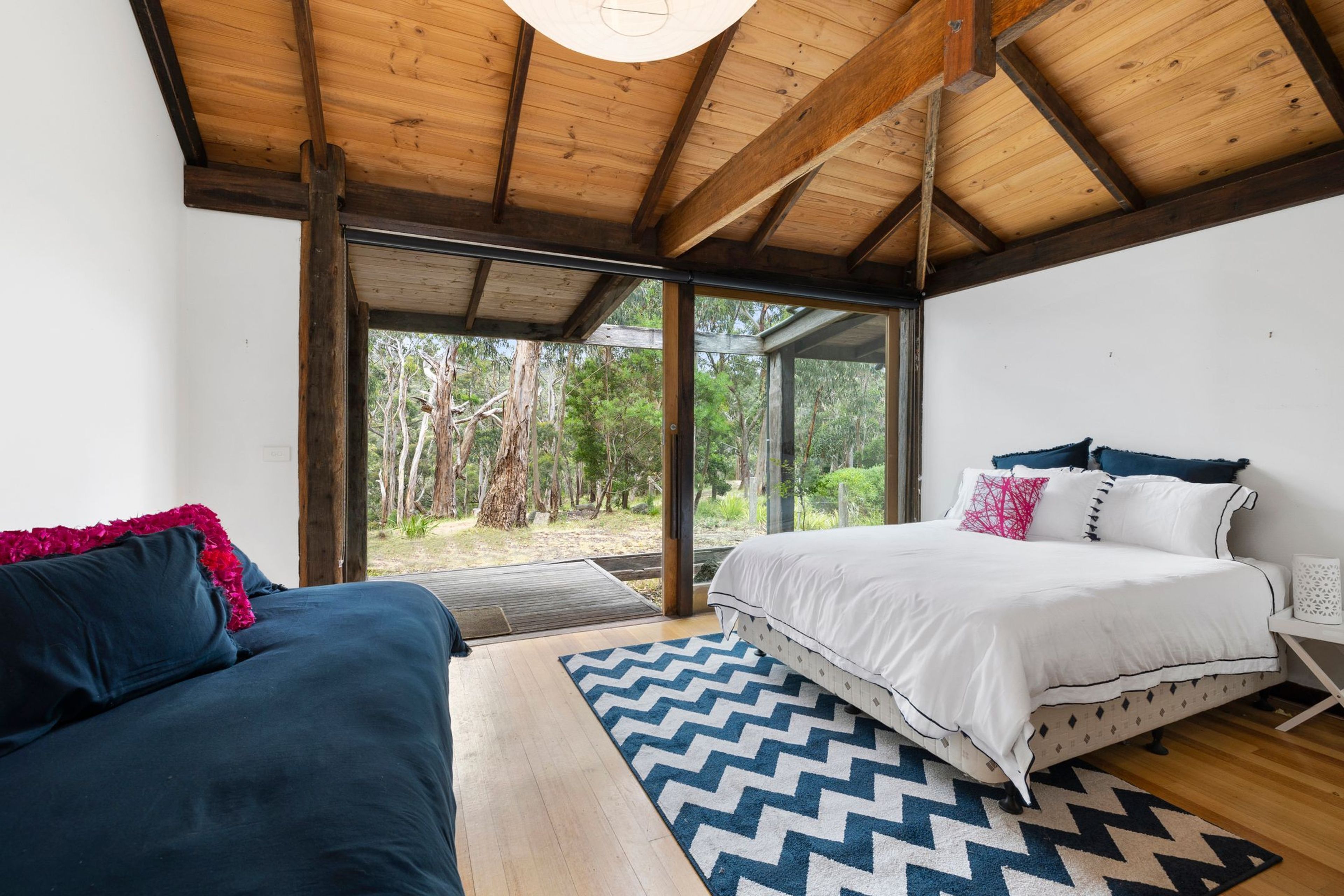Een slaapkamer met een bed, een bank en een groot raam.