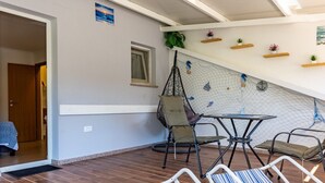 A cozy indoor seating area with a hanging chair, a small table, and striped lounge chairs.