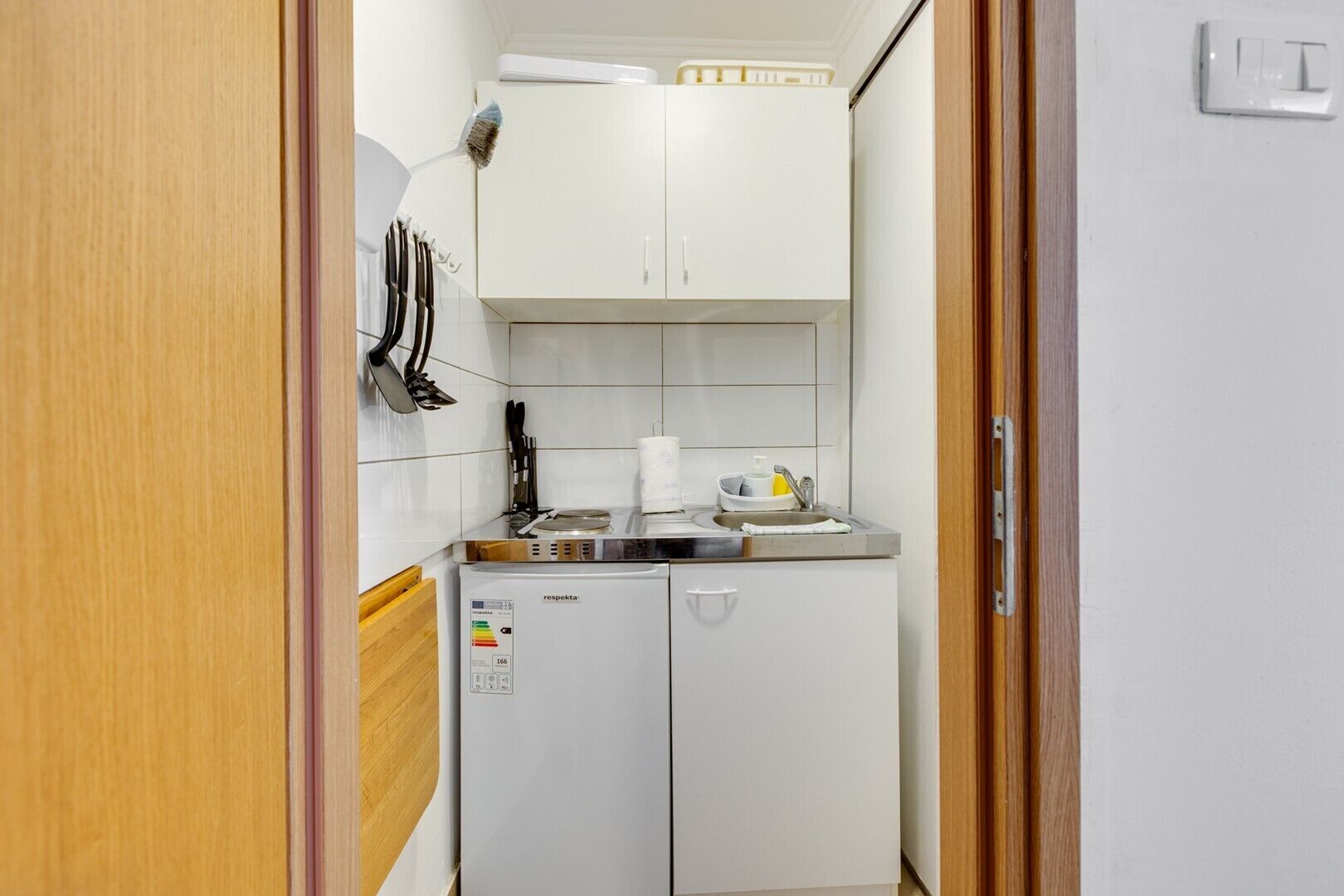 A compact kitchenette with a refrigerator, a sink, and a stove.
