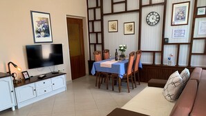 Een woonkamer met een televisie, eettafel en bank.