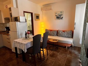 En kompakt bolig med tekøkken, spiseplads, sofa og et lille bord.