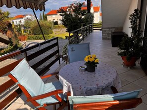 En balkon med et bord, stole og blomsterkrukker.
