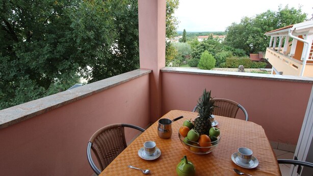Ein Balkon mit Tisch für zwei Personen, ausgestattet mit Obstschale, Teekanne und Tassen.