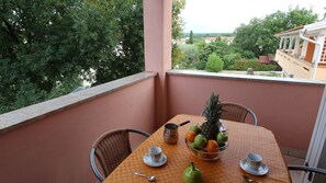 Ein Balkon mit Tisch für zwei Personen, ausgestattet mit Obstschale, Teekanne und Tassen.