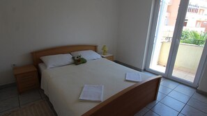 Ein Schlafzimmer mit Bett, Nachttisch, Lampe und Blick ins Freie.