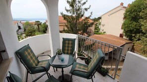 A balcony with two chairs and a table, overlooking a residential area with houses and a body of water. - Cozy apartment Kovačić 2 on the island of Krk (Malinska)