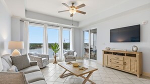 Ein großzügiges Wohnzimmer mit einer Couch, Sesseln, einem Couchtisch und einem Fernseher.