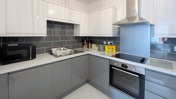 A modern kitchen with white cabinets, a stainless steel range hood, a built-in oven, and a black microwave. - Anstey Heights - Apartment 8 - Hopewell (Easton)