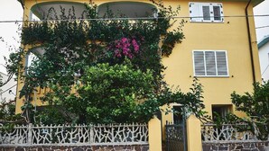 A yellow building with a stone wall and a metal gate. - Appartamento Iris 2- IUN P2186 Rose (Cala Gonone)