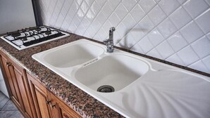 A kitchen with a double sink, a gas stove, and wooden cabinets. - Appartamento Iris 2- IUN P2186 Rose (Cala Gonone)