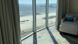 Ein Zimmer mit großem Fenster und Blick auf einen Strand.