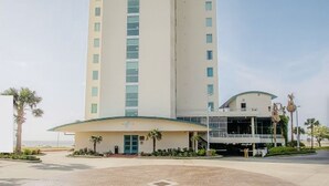 Ein Hotel mit Innenhof, ein hohes Gebäude mit gewölbter Dachform und Palmen.