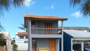 A two-story building with a balcony, a wooden bench outside, and a clear blue sky.