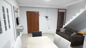 A modern living room with a dining table, a sofa, and a staircase.