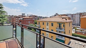 A balcony with a view of a cityscape, featuring multi-story buildings with balconies and a clear sky. - San Donato Bologna Fiere Apartment (Bologna)