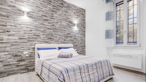 A bedroom with a bed, a window, and a wall with a textured pattern.
