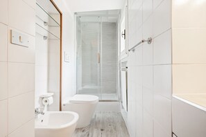 Un baño moderno con cabina de ducha de vidrio, inodoro y lavamanos.