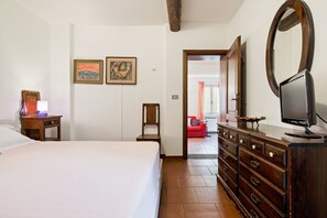 Una habitación de hotel con cama, cómoda de madera y espejo. Hay dos cuadros en la pared.