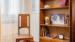 Ein Holzsessel und ein Bücherregal mit Büchern, Dekoration und einer Uhr.