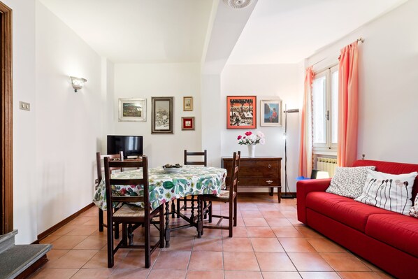 Un comedor con una mesa, sillas, un sofá rojo y un televisor.