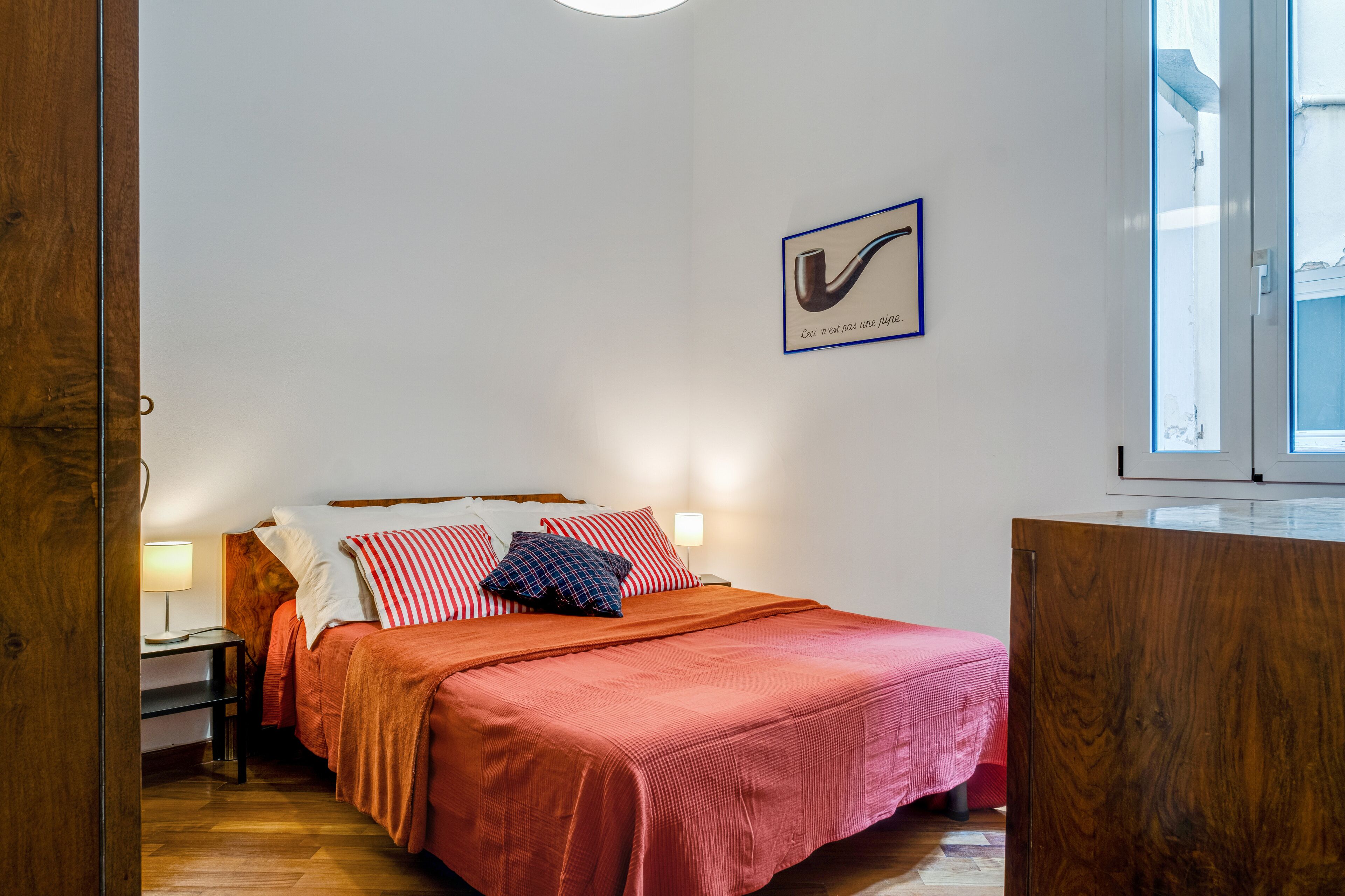 Una camera da letto con un letto di legno, un comodino, una lampada e un quadro appeso al muro.