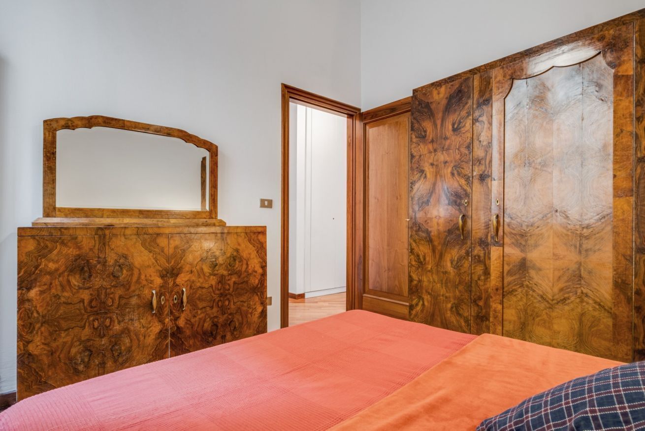 A bedroom with a bed, a wooden wardrobe, and a mirror.