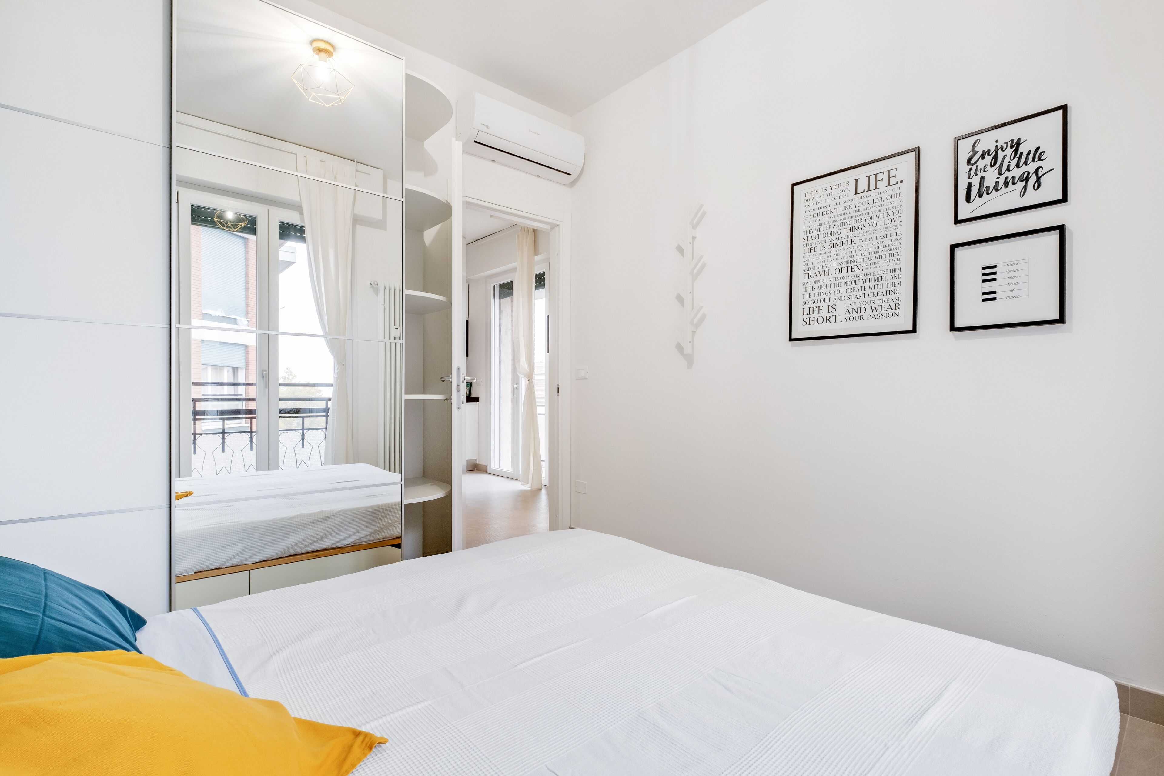 Een slaapkamer met een bed, een kledingkast en een raam. Op de muur hangen drie ingelijste citaten.