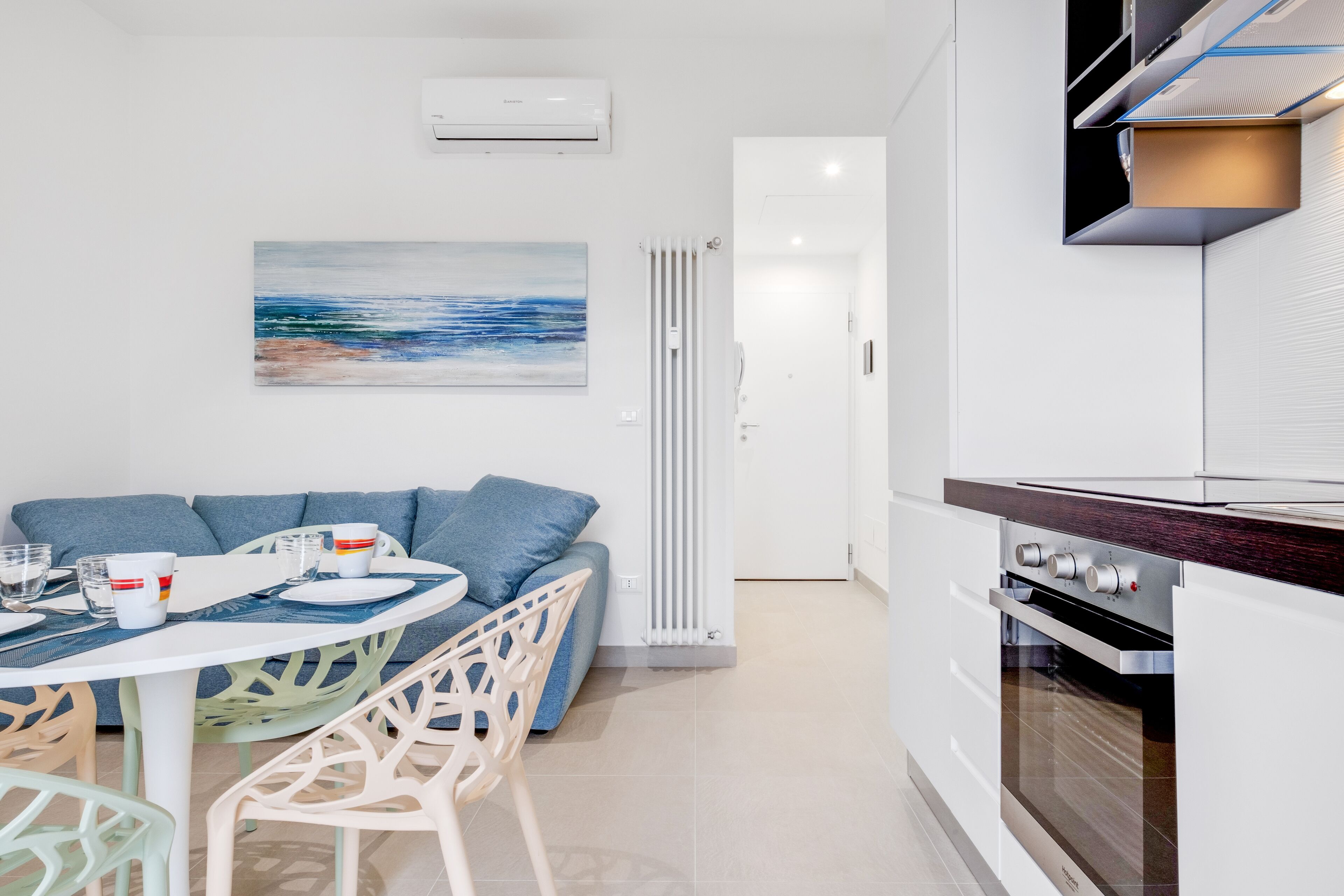 Une cuisine moderne avec des meubles blancs, un four encastré et un coin repas comprenant une table et des chaises.