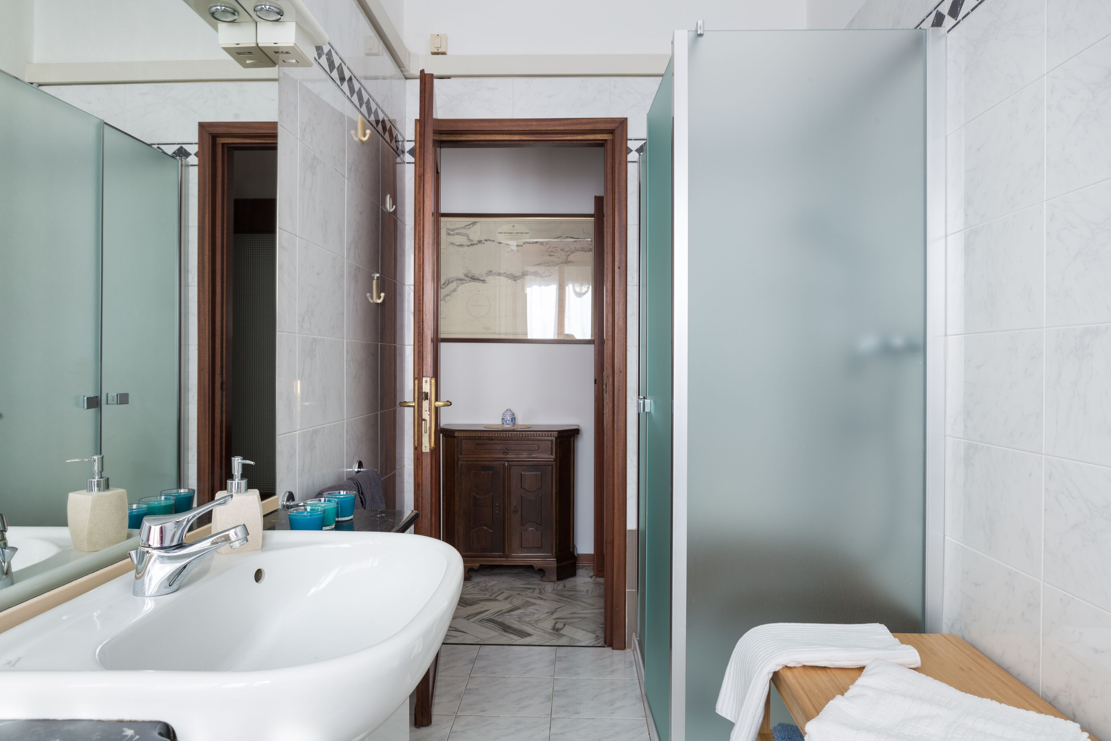 A bathroom with a large sink, mirror, and wooden cabinet.