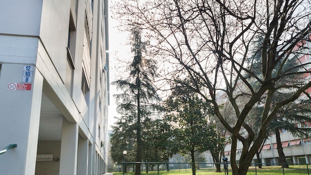 A building with a covered walkway and trees in the background. - Apartment Surrounded by Greenery (Parma)