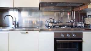 A modern kitchen with stainless steel appliances, including a sink, stove, and oven. - Apartment Surrounded by Greenery (Parma)