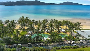 A resort with a pool, palm trees, and a view of the ocean.