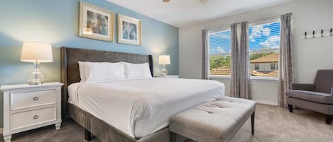 A bedroom with a bed, two bedside tables, a chair, a ceiling fan, and a window with curtains.