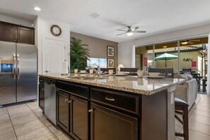 A kitchen with a central island, stainless steel appliances, and a ceiling fan. - Stunning 5BR Townhouse w Pool & Theme Room (Kissimmee)