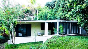 Una casa moderna con porche cubierto, rodeada de abundante vegetación.