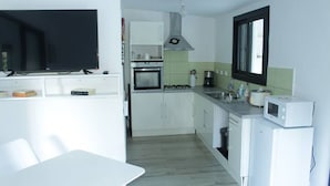 Una cocina compacta con armarios blancos, estufa, microondas y pileta.