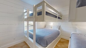 Uma cama de solteiro com janela, mesa de cabeceira e abajur.