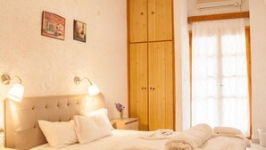 Une chambre à coucher avec un lit, une armoire en bois, des lampes de chevet et une fenêtre avec des rideaux.