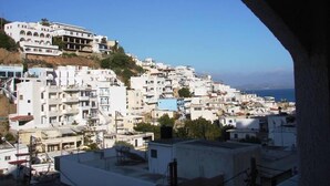 A coastal town with white buildings, a clear sky, and a view through an archway. - Gioma Hotel (Agios Vasileios)