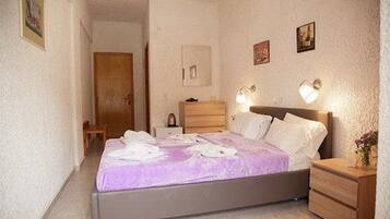 A bedroom with a bed, bedside tables, a dresser, and wall-mounted lamps.