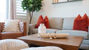 Un salon comprenant un canapé, une table basse agrémentée d’objets décoratifs et une grande plante.