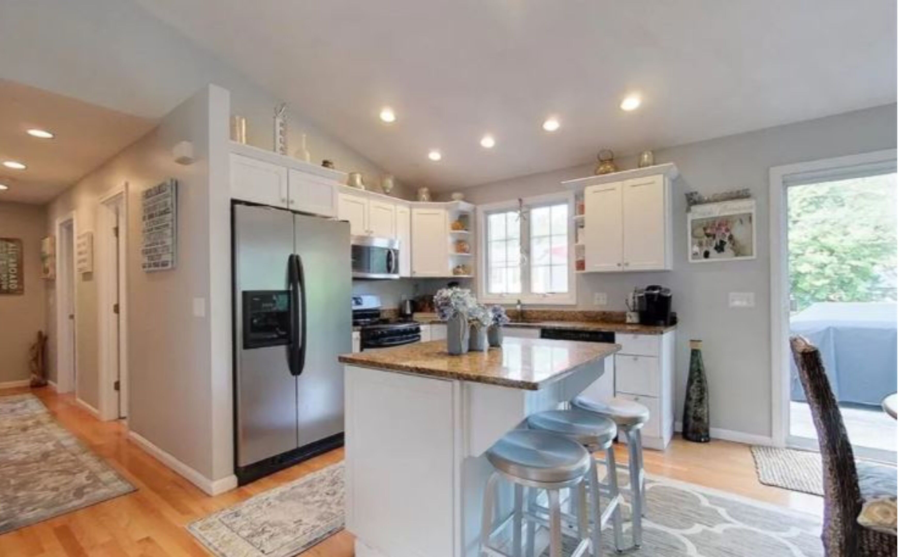 A modern kitchen with white cabinets, stainless steel appliances, and a central island with bar stools.