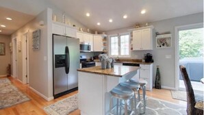A modern kitchen with white cabinets, stainless steel appliances, and a central island with bar stools.