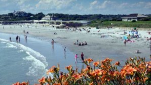 A beach with people swimming and walking along the shore.