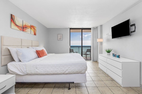 Relax in a serene space with a large bed, flat-screen TV, and ocean views from the balcony.