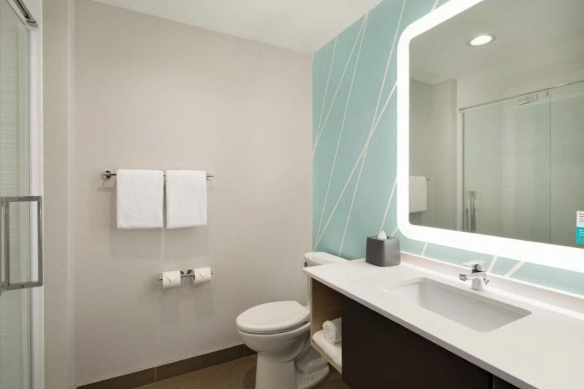 A modern bathroom with a toilet, sink, and mirror.